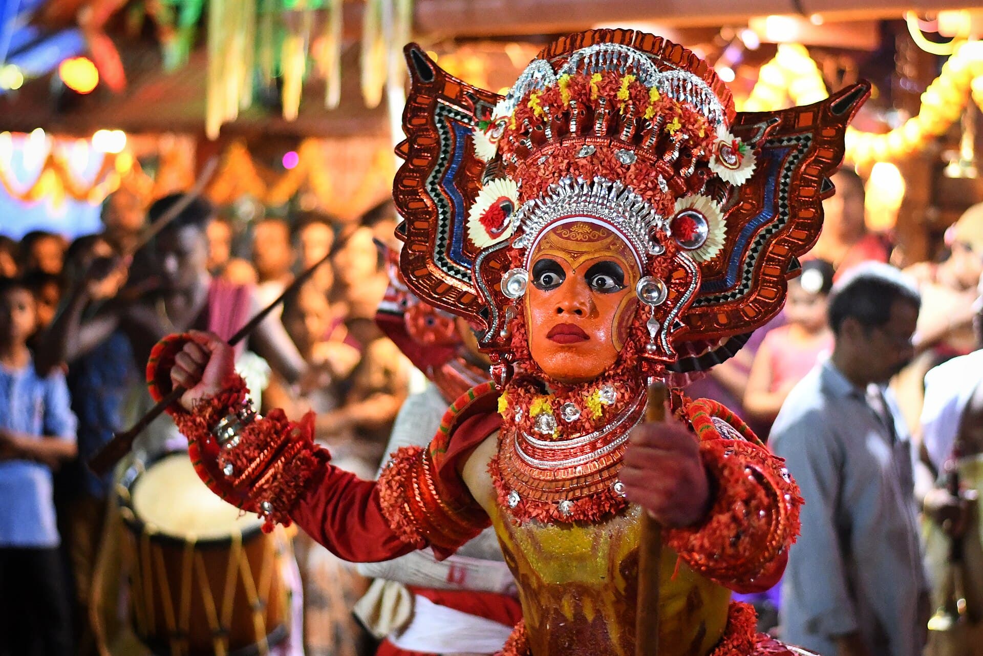 A Theyyam performer in full ritual costume and headdress in Kannur